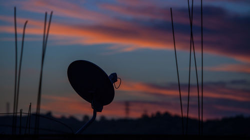 Low angle view of silhouette telephone against sky during sunset