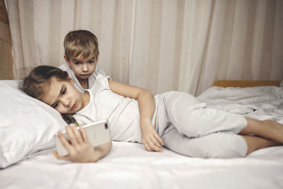 Siblings watching video in mobile devices in bed, gadget dependence and addiction, online lifestyle