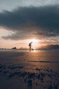 Silhouette person on beach against sky during sunset