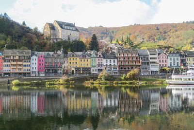 Buildings by river against sky