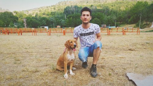 Portrait of young man with dog on land