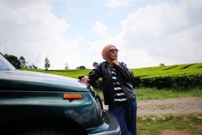 Young woman standing on road against sky