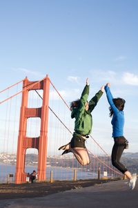 Digital composite image of friends jumping against golden gate bridge