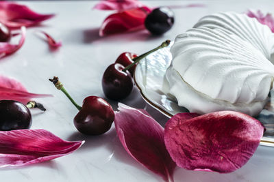 Close-up of cherries and petals by marshmallow on table