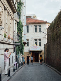 People walking on street amidst buildings in city