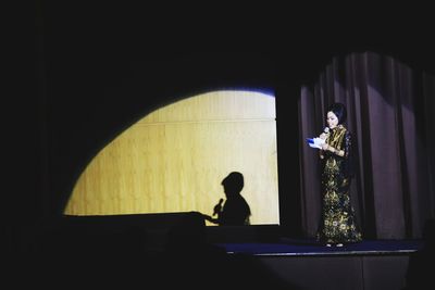 Rear view of man and woman standing in illuminated room