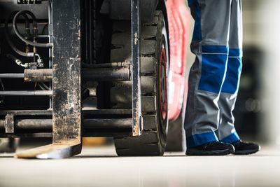 Low section of worker standing on forklift