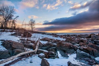 Close-up of snow on shore against sky during sunset