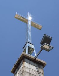 Low angle view of cross against building against clear blue sky