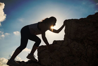 Man standing on rock against sky during sunset