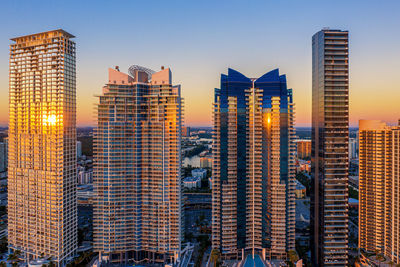 Modern buildings in city against sky during sunrise