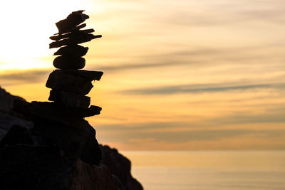 Stack of rocks on beach against sky during sunset