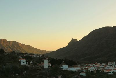 Townscape by mountains against sky during sunset
