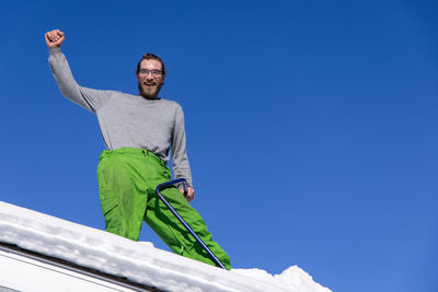 Low angle view of man against clear blue sky