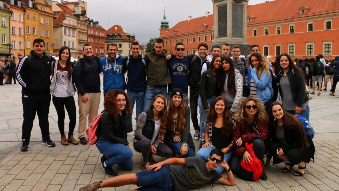 large group of people, real people, building exterior, sitting, architecture, men, full length, casual clothing, leisure activity, women, outdoors, built structure, city, day, young women, lifestyles, young adult, crowd, togetherness, adult, people, adults only