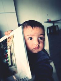 Close-up of cute baby boy looking away at home