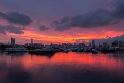 Sea and buildings against sky during sunset