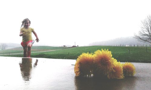 Full length of young woman on field against clear sky