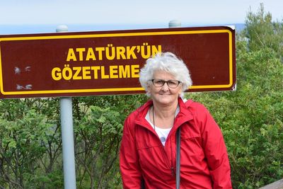 Portrait of woman sitting against information sign