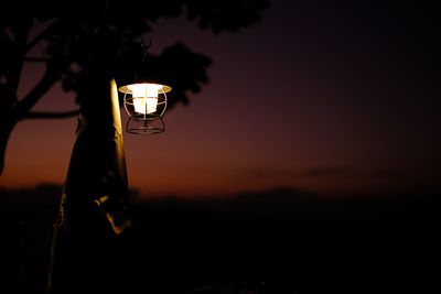 Close-up of illuminated light bulb against sky during sunset