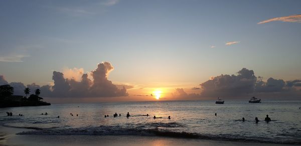 Silhouette people on beach against sky during sunset