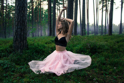 Woman sitting on field in forest