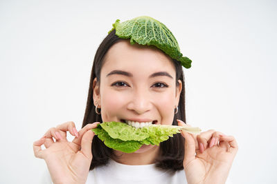 Portrait of young woman holding plant against white background