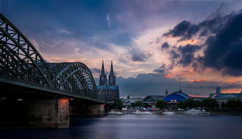 View of bridge over river against cloudy sky during sunset