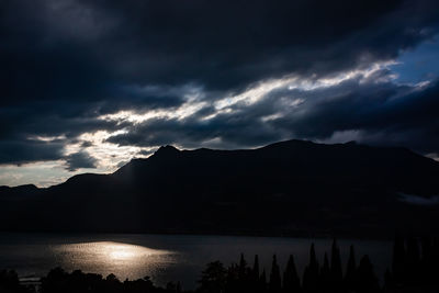 Scenic view of lake and silhouette mountains against sky