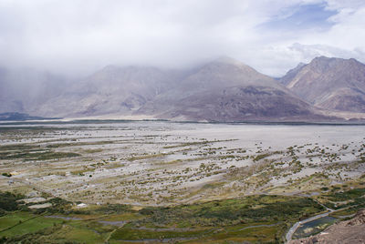 Scenic view of lake by mountains against sky