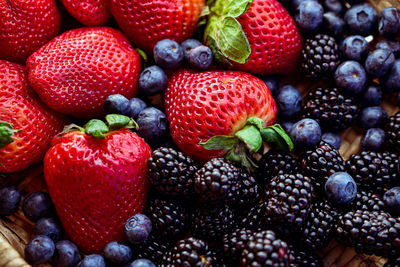 Woven basket of red strawberries, blueberries, and blackberries