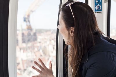 Side view of woman looking through window