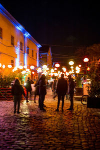 People on illuminated street at night