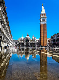 Reflection of building in water against clear blue sky