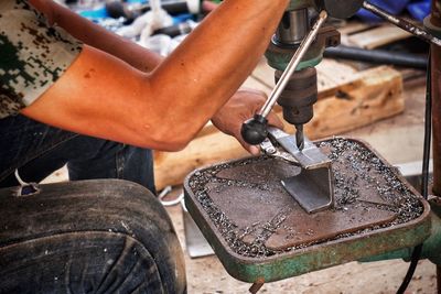 Midsection of man working on metal