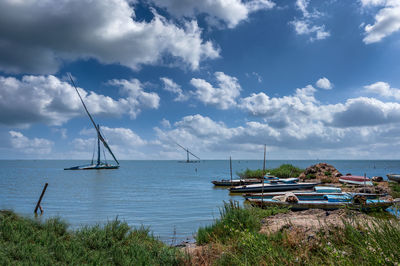 Sailboats moored on sea against sky