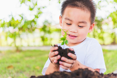 Close-up of cute boy holding seedling outdoors