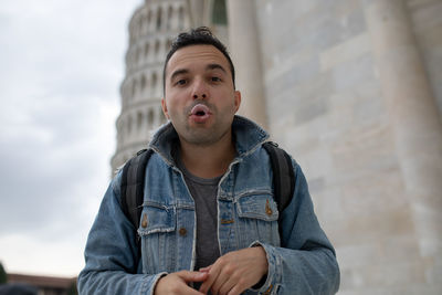 Low angle view of man blowing bubble gum while standing against built structure