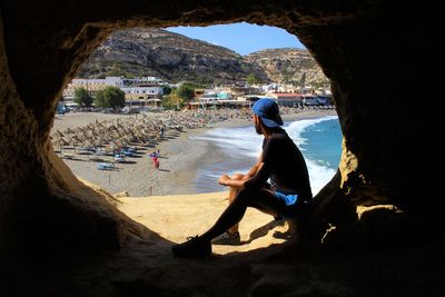 Man sitting on rock at beach