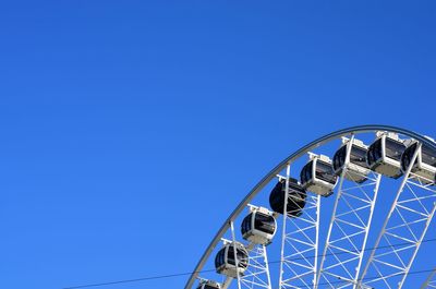 Low angle view of ferris wheel against clear blue sky