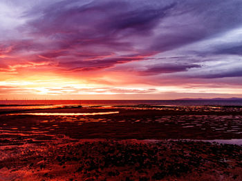 Scenic view of sea against dramatic sky during sunset