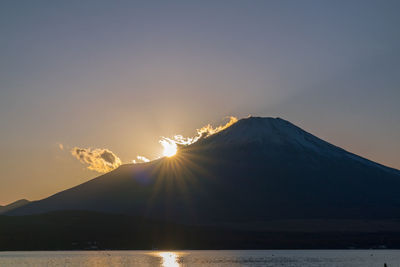 Scenic view of volcanic mountain against sky during sunset