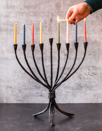 Cropped image of a hand lighting candles on menorah for hanukkah.
