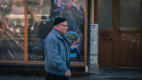 Midsection of man standing by window in city