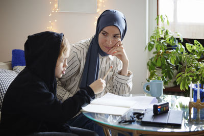 Mother wearing hijab helping son with add or adhd doing homework