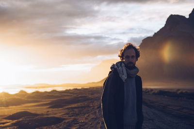 Portrait of man standing on field against sky during sunset