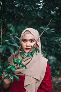 Portrait of young woman holding leaves outdoors