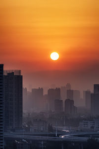 Buildings in city against sky during sunset