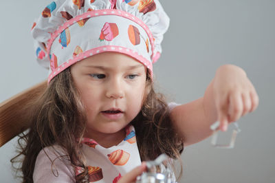 A young girl is playing chef at the kitchen table.