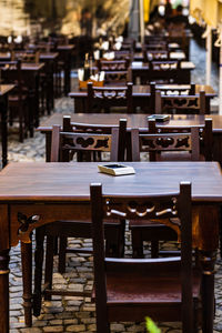 Empty chairs and tables at sidewalk cafe by building